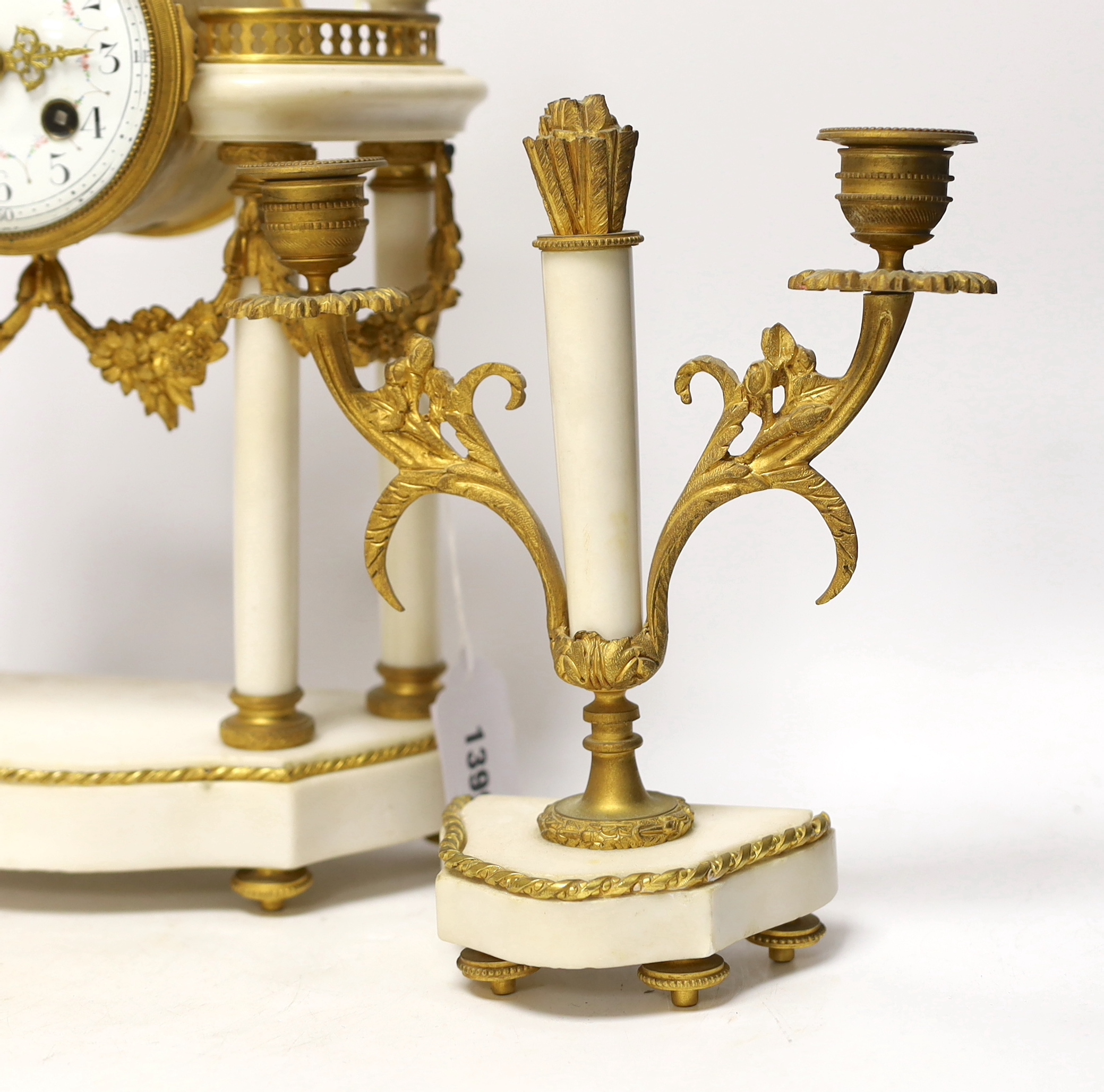 A 19th century French ormolu and white marble clock garniture striking on a gong, the dial decorated with swags, 40cm high